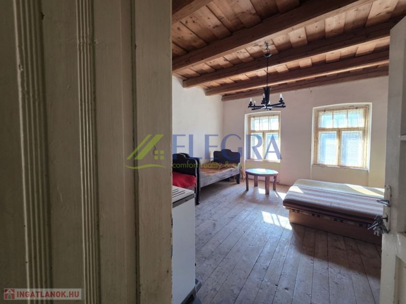 Ein Zimmer in einem Einfamilienhaus mit einer Holzdecke und einfacher Einrichtung.