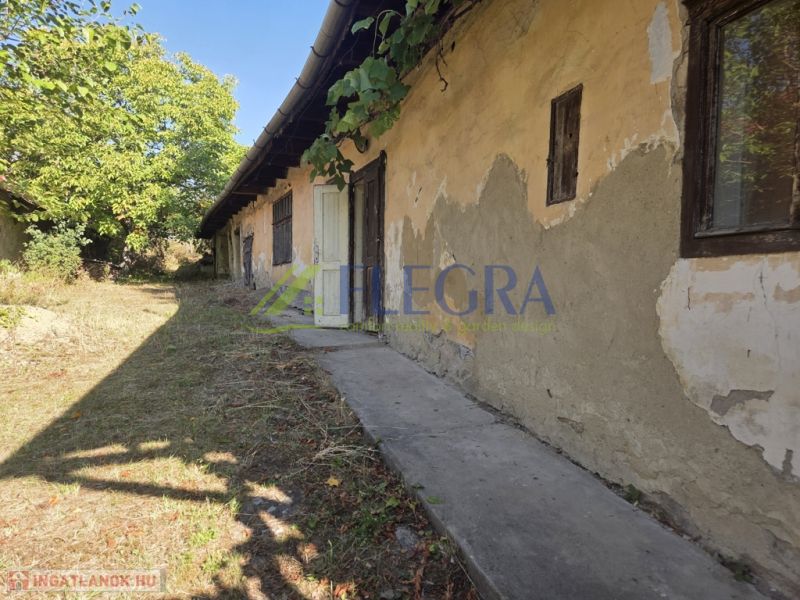 Ein Einfamilienhaus in Hejce, das renoviert werden muss, mit altem Putz und einem gepflegten Garten.