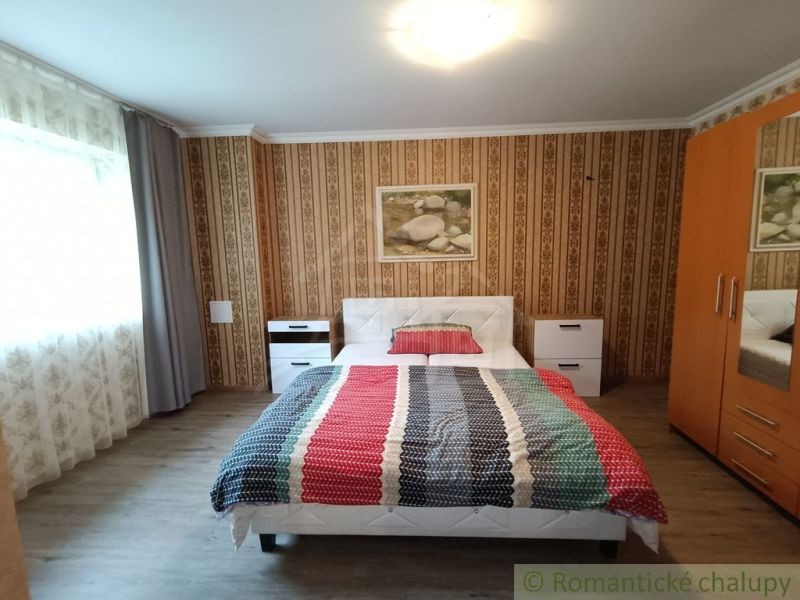 Schlafzimmer im Einfamilienhaus mit Holzboden und gestreifter Bettwäsche.