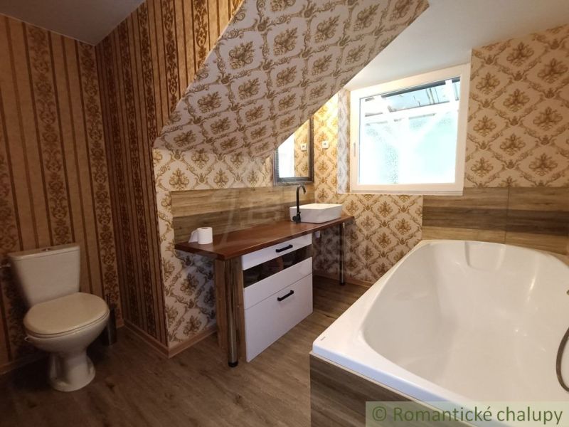 Badezimmer in einem Einfamilienhaus mit Tapeten und Bodenbelag in Holzoptik.