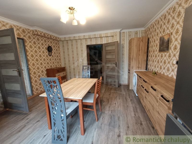 Esszimmer in einem Einfamilienhaus mit gemusterten Tapeten und einem Boden in Holzoptik.