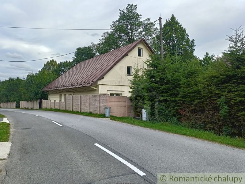 Ein Einfamilienhaus in Staškov mit einem Blechdach, umgeben von Bäumen und einem Zaun.