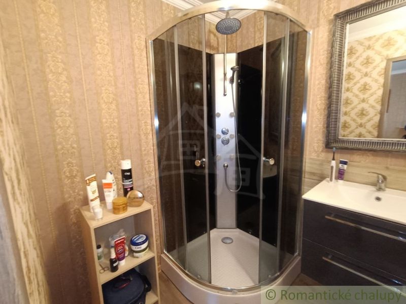 Badezimmer im Einfamilienhaus mit runder Duschkabine und Spiegel.