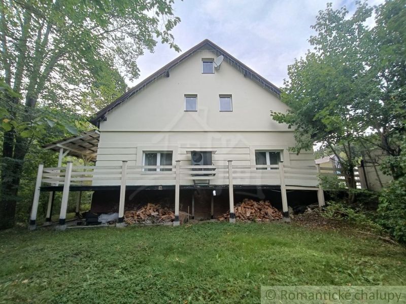 Ein Einfamilienhaus in Staškov, umgeben von Grün, mit Holz unter der Terrasse gelagert.