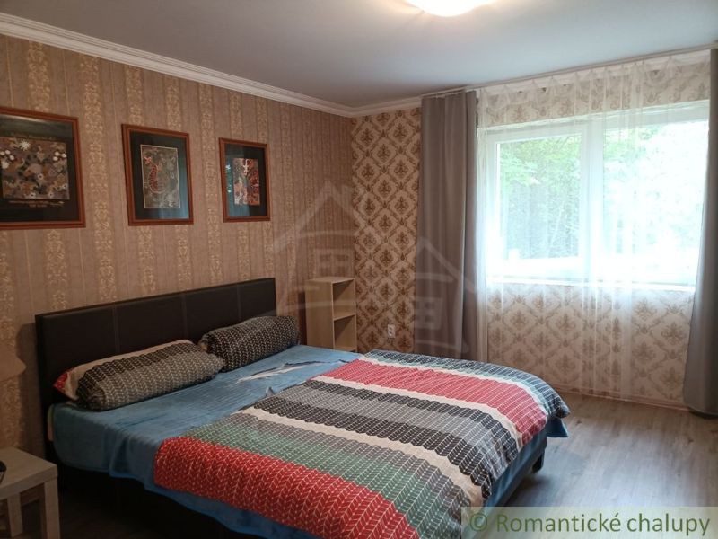 Schlafzimmer in einem Einfamilienhaus mit Doppelbett, Fenster und dekorativen Tapeten.