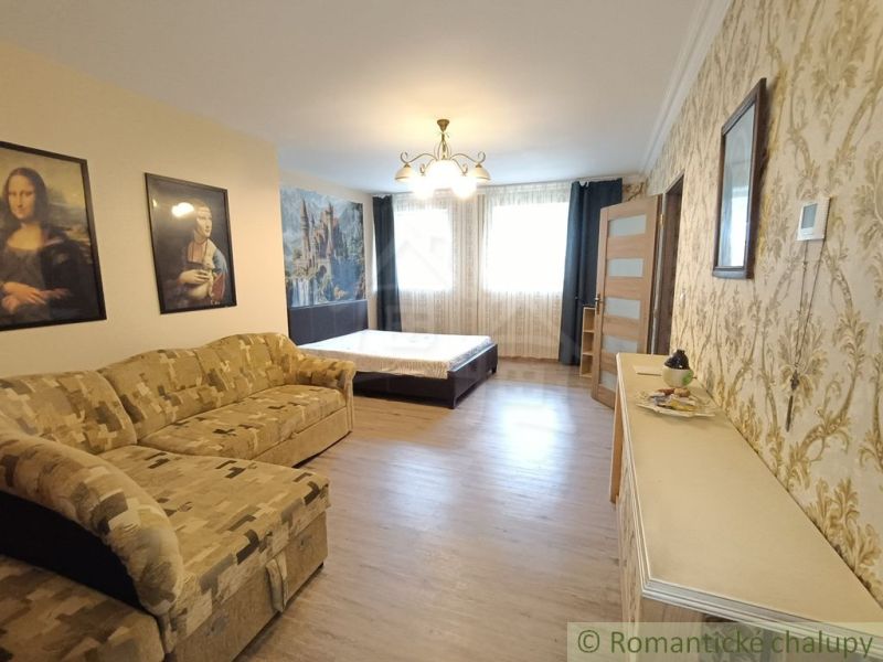 Innenraum eines Einfamilienhauses mit Sofa, Bett und Holzboden.