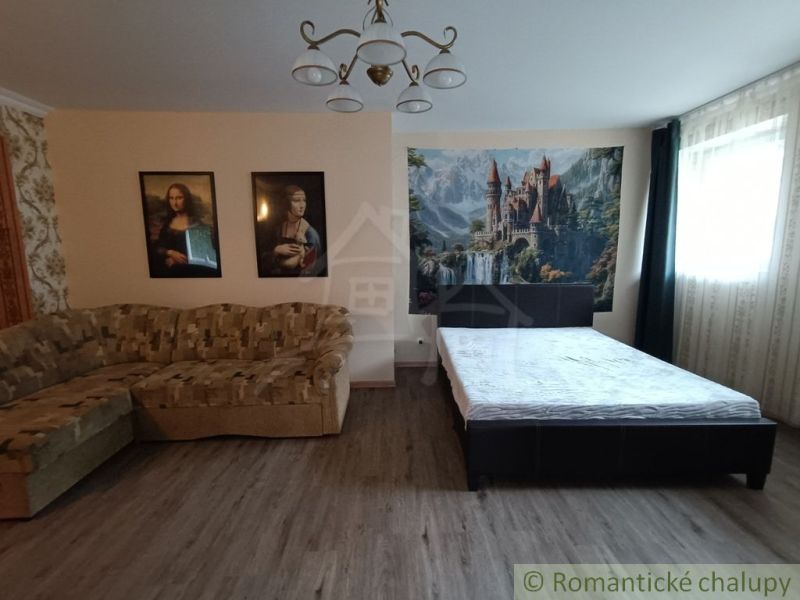 Ein Zimmer in einem Einfamilienhaus mit einem Bett, einem Sofa und Bildern an der Wand.
