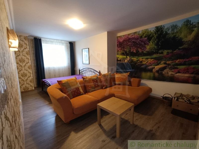 Wohnzimmer in einem Einfamilienhaus mit einem orangefarbenen Sofa und einer Naturtapete.