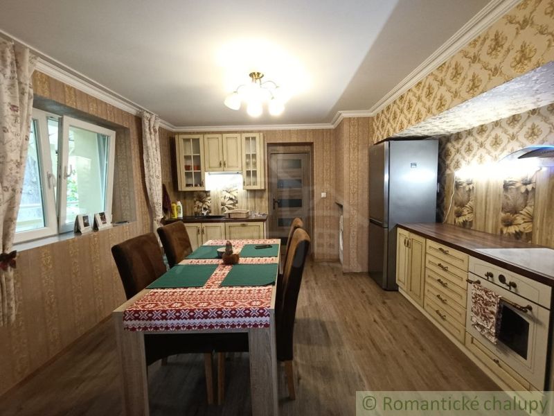 Eine Küche in einem Einfamilienhaus mit gemusterten Tapeten und einem Boden in Holzoptik.