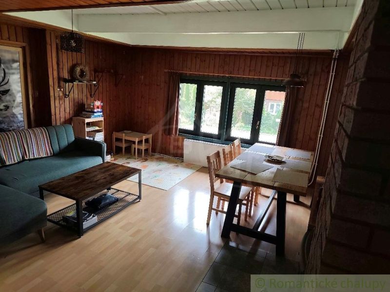 Wohnzimmer in einer Hütte mit Holzboden und Essecke.