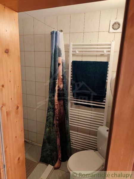 Badezimmer in der Hütte mit gefliester Wand, Vorhang und Heizelement.
