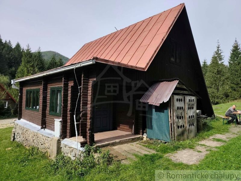 Eine Hütte in Rajecká Lesná mit einem Blechdach und Holzwänden, umgeben von Natur.