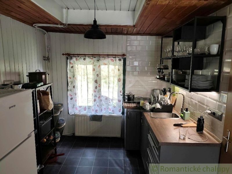Eine Küche in einer Hütte mit ländlicher Atmosphäre und Holzdekor an der Decke.