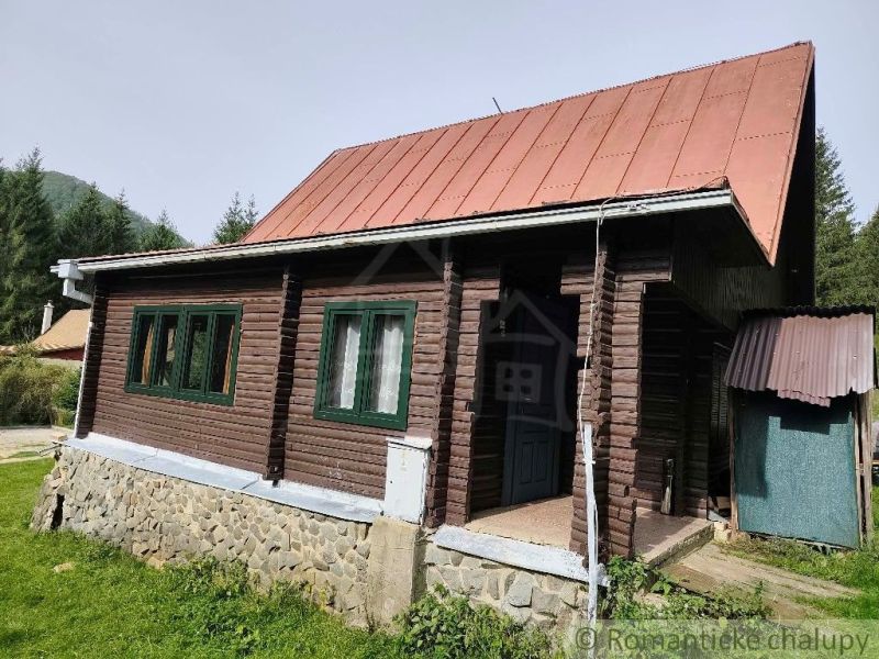 Eine Holzhütte mit Blechdach in der Natur von Rajecká Lesná, umgeben von Grün.