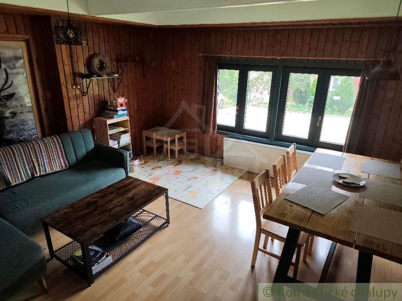 Wohnzimmer der Hütte mit einem bequemen Sofa und einem Tisch, Boden mit Holzdekor.