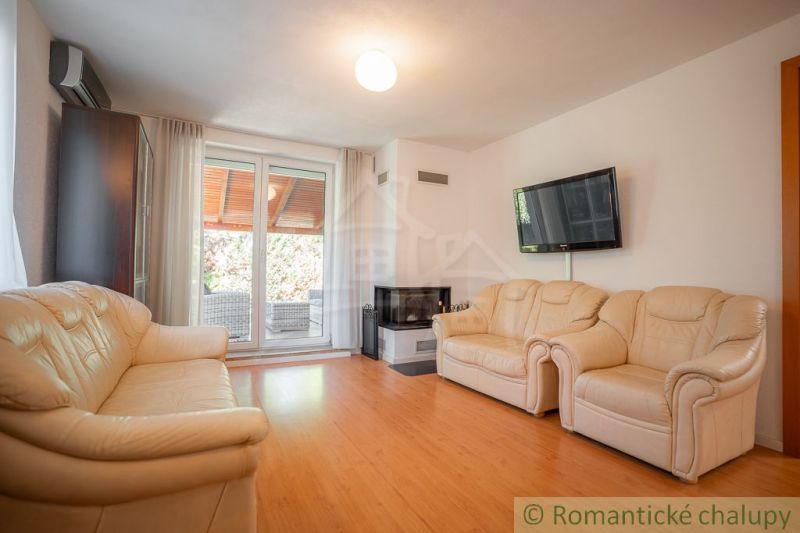 Wohnzimmer in einem Einfamilienhaus mit Fernseher, Kamin und Boden mit Holzdekor.