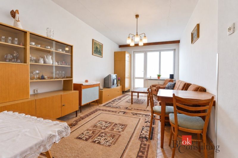 Wohnzimmer einer 2-Zimmer-Wohnung mit Retro-Möbeln, Teppich und Glasvitrine.