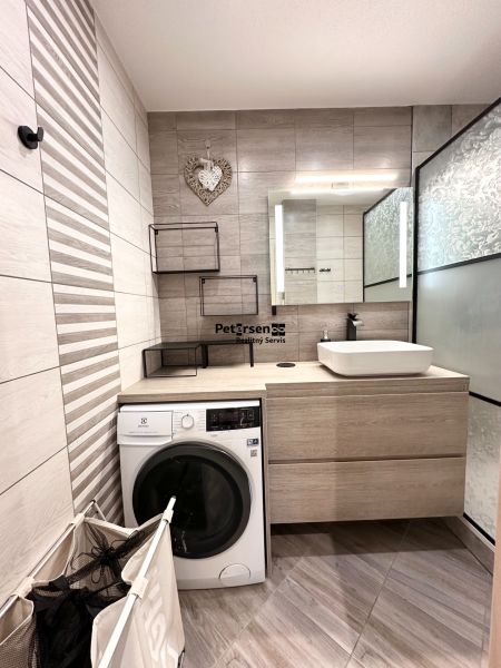 Badezimmer in einer 3-Zimmer-Wohnung mit Waschmaschine, Waschbecken und dekorativen Fliesen.