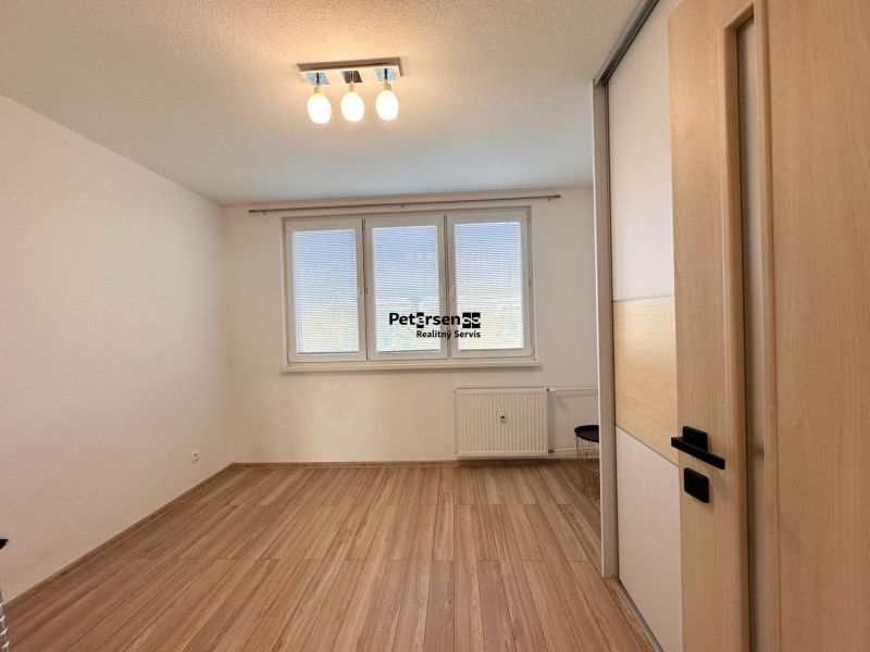 Ein geräumiges Zimmer mit einem Holzboden in einer 3-Zimmer-Wohnung.