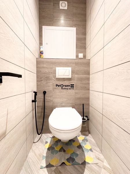 Badezimmer mit Toilette und Holzboden in einer 3-Zimmer-Wohnung.