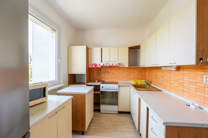 Küche in einer 3-Zimmer-Wohnung, mit orangefarbenen Fliesen und einem Boden in Holzoptik.