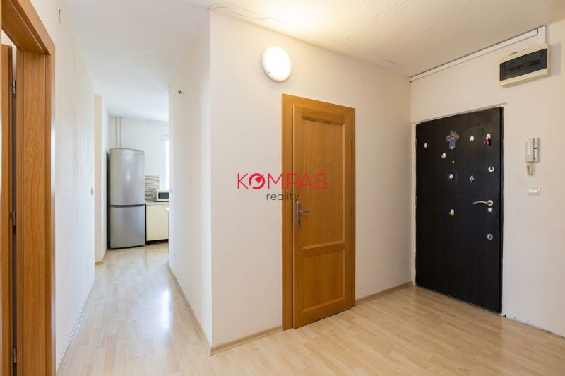 Eingangsbereich in einer 3-Zimmer-Wohnung mit Holzboden und Küche mit Geräten.