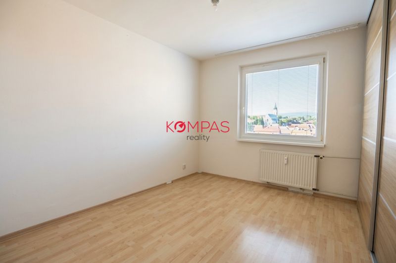 Zimmer in einer 3-Zimmer-Wohnung, Boden mit Holzdekor, großes Fenster mit Aussicht.