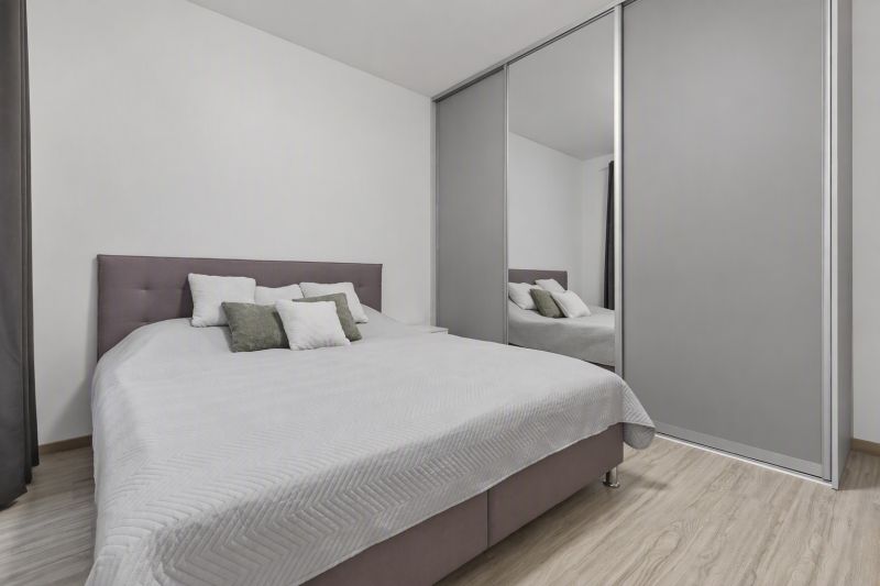 Schlafzimmer mit großem Bett, Einbauschrank und Holzboden in einer Zweizimmerwohnung.