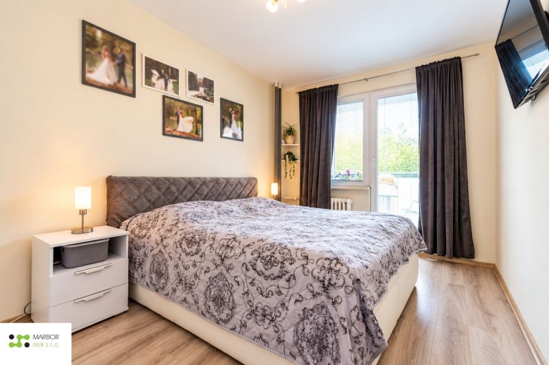 Schlafzimmer mit dekorativem Bett, Nachttisch und Vorhängen in einer 3-Zimmer-Wohnung.