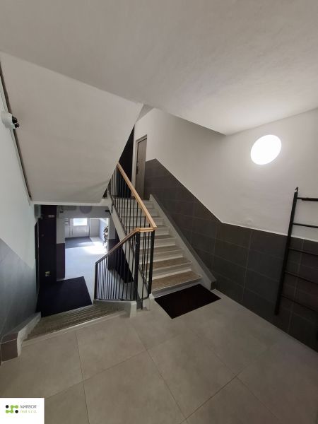 Treppenhaus eines Apartmenthauses in einer 3-Zimmer-Wohnung mit modernen Fliesen und Geländer.