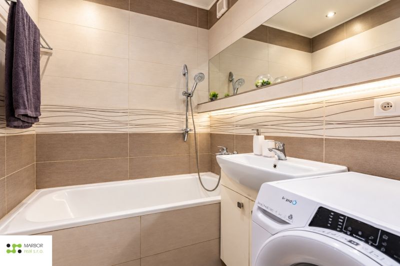 Badezimmer mit Badewanne und Waschbecken in einer 3-Zimmer-Wohnung mit Spiegel und Waschmaschine.