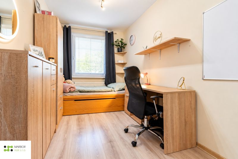 Ein Arbeitszimmer mit Bett, Schreibtisch und Regal, Holzboden in einer 3-Zimmer-Wohnung.