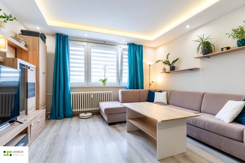 Wohnzimmer in einer 3-Zimmer-Wohnung mit Holzboden und blauen Vorhängen.