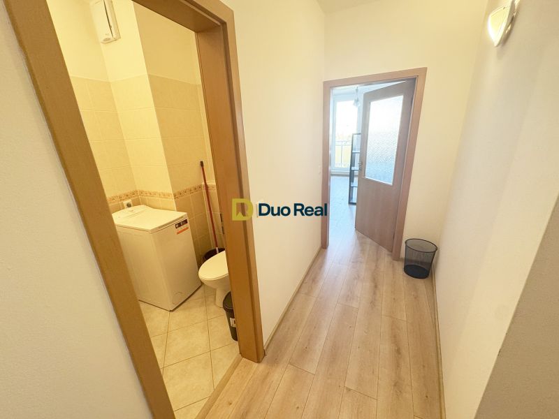 Der Flur des Einzimmerapartments mit einem Boden in Holzoptik und einem Eingang zum Badezimmer.