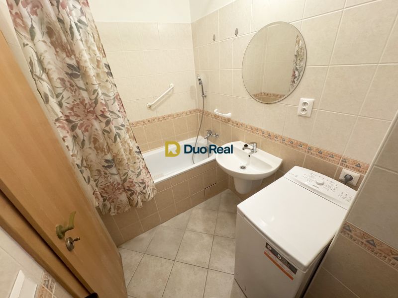 Badezimmer in einem Studio-Apartment mit Waschbecken, Badewanne und Waschmaschine.