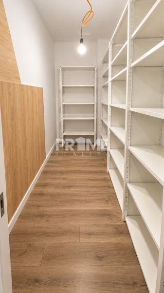 Stauraum mit weißen Regalen und einem Boden in Holzoptik in einer 2-Zimmer-Wohnung.