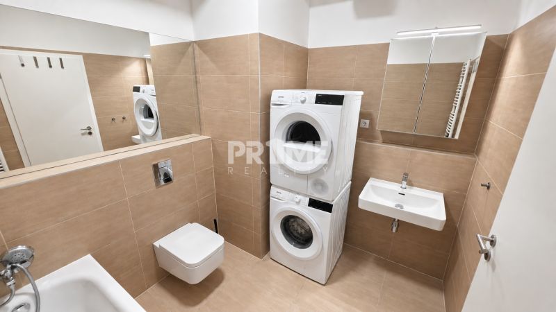 Badezimmer einer Zweizimmerwohnung mit Dusche, Waschbecken, Toilette und Waschmaschine mit Trockner.