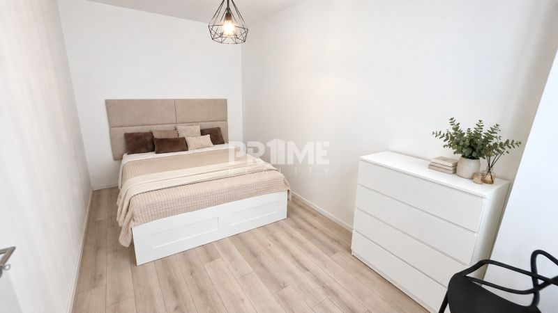 Ein Zimmer in einer 2-Zimmer-Wohnung mit einem Bett, einer Kommode und einem Boden mit Holzdekor.