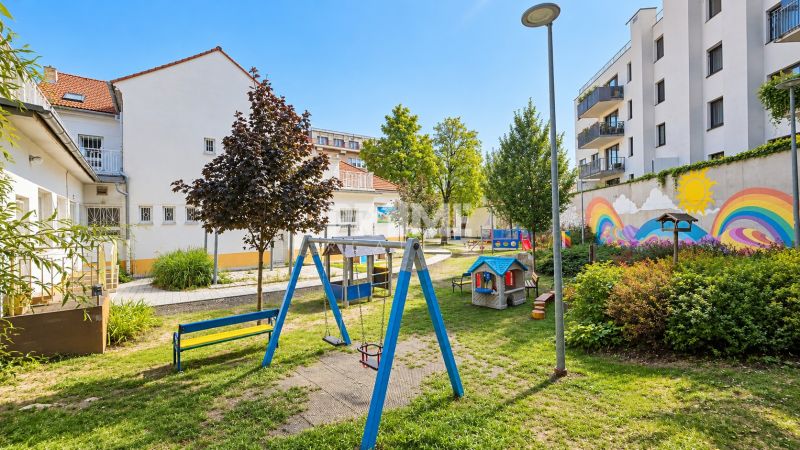 Ein Kinderspielplatz umgeben von Gebäuden mit bunten Wandmalereien in der Sancova-Straße.