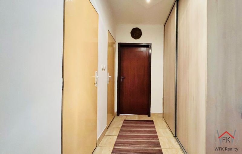 Flur in einer 3-Zimmer-Wohnung mit Stauraum und Teppich in warmen Tönen.