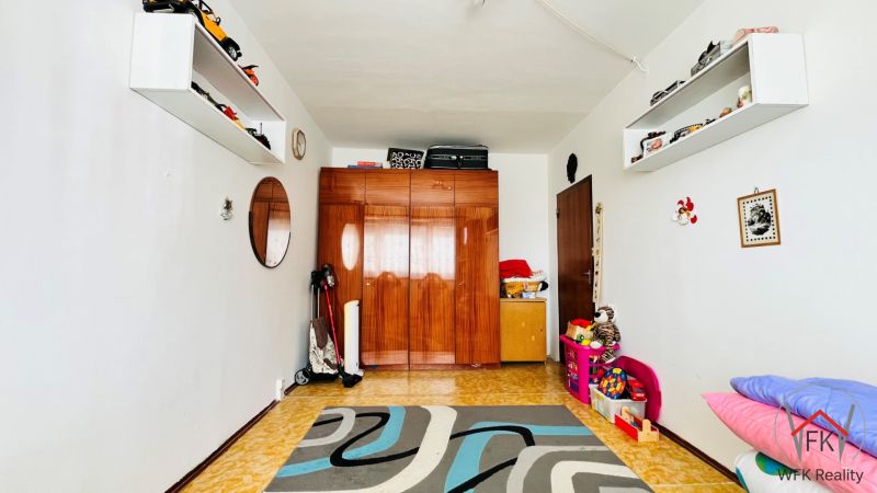 Ein Zimmer in einer 3-Zimmer-Wohnung mit Teppich, Spielzeug und einem Schrank mit Holzdekor.
