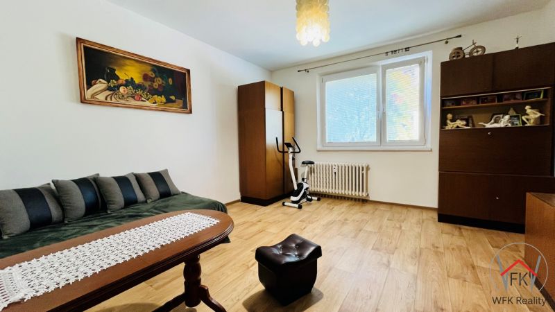 Ein Zimmer in einer 3-Zimmer-Wohnung mit einem Holzboden, Vintage-Möbeln und einem Bild an der Wand.