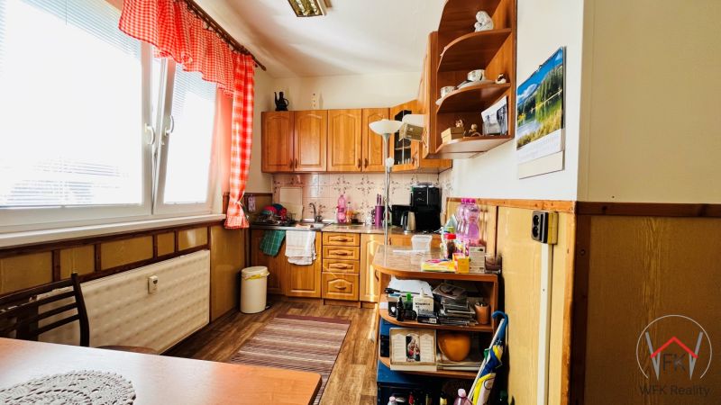 Küche in einer 3-Zimmer-Wohnung, mit Holzboden, roten Vorhängen und Ausstattung.
