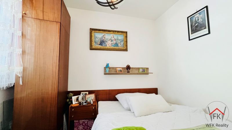 Schlafzimmer in einer 3-Zimmer-Wohnung mit einem Bild und einem Wandregal über dem Bett.