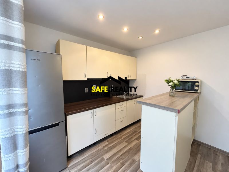 Küche mit Holzboden, hellen Schränken und Kühlschrank in einer Einzimmerwohnung.
