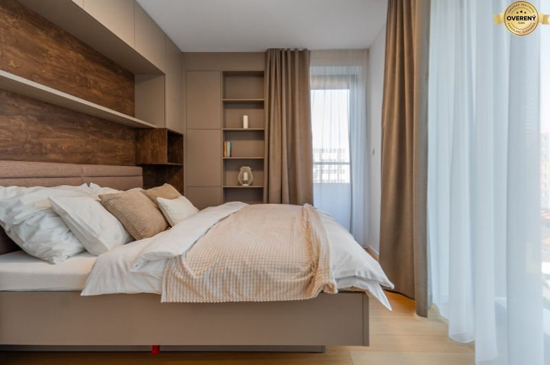 Helles Schlafzimmer mit beigen Vorhängen, Regalen und einem Boden mit Holzdekor im Projekt Wohnungsbau.