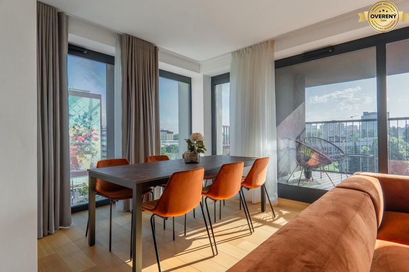 Essbereich mit orangefarbenen Stühlen, Holzboden, Zugang zum Balkon. Wohnungsbau.
