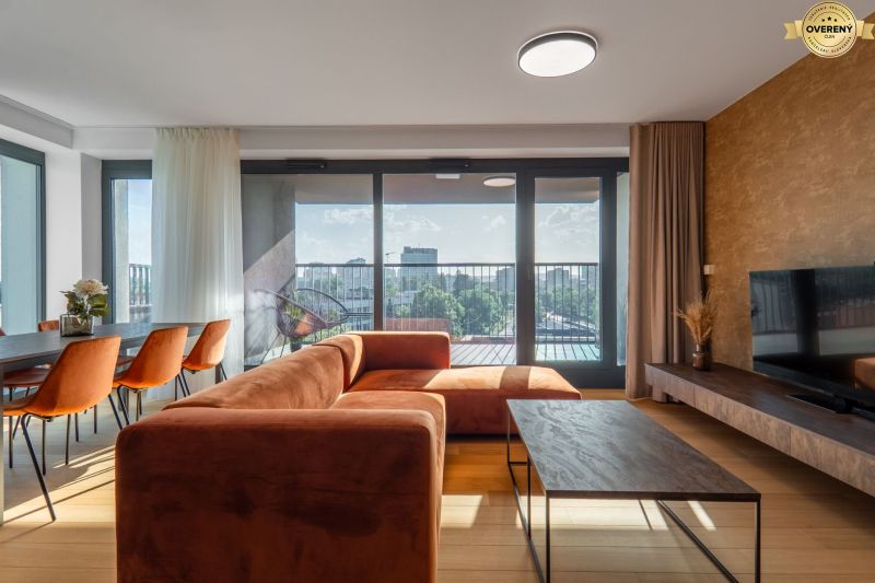 Wohnzimmer mit orangefarbenem Sofa, Esstisch und Blick auf die Stadt. Wohnungsbau.