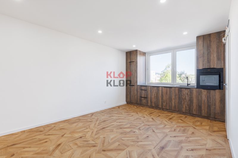 Küche in einer 2-Zimmer-Wohnung mit Holzboden und Einbauschränken.
