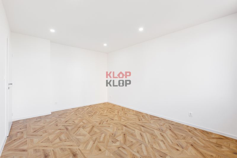 Ein Zimmer in einer 2-Zimmer-Wohnung mit weißen Wänden und einem Boden in Holzoptik.